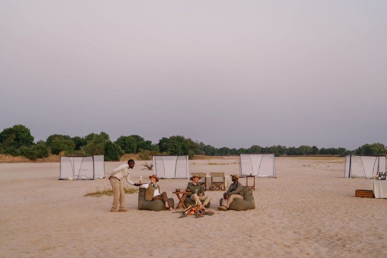 Drinks ved bålet på Time + Tide Sleepout Under the Stars, Zambia, Afrika
